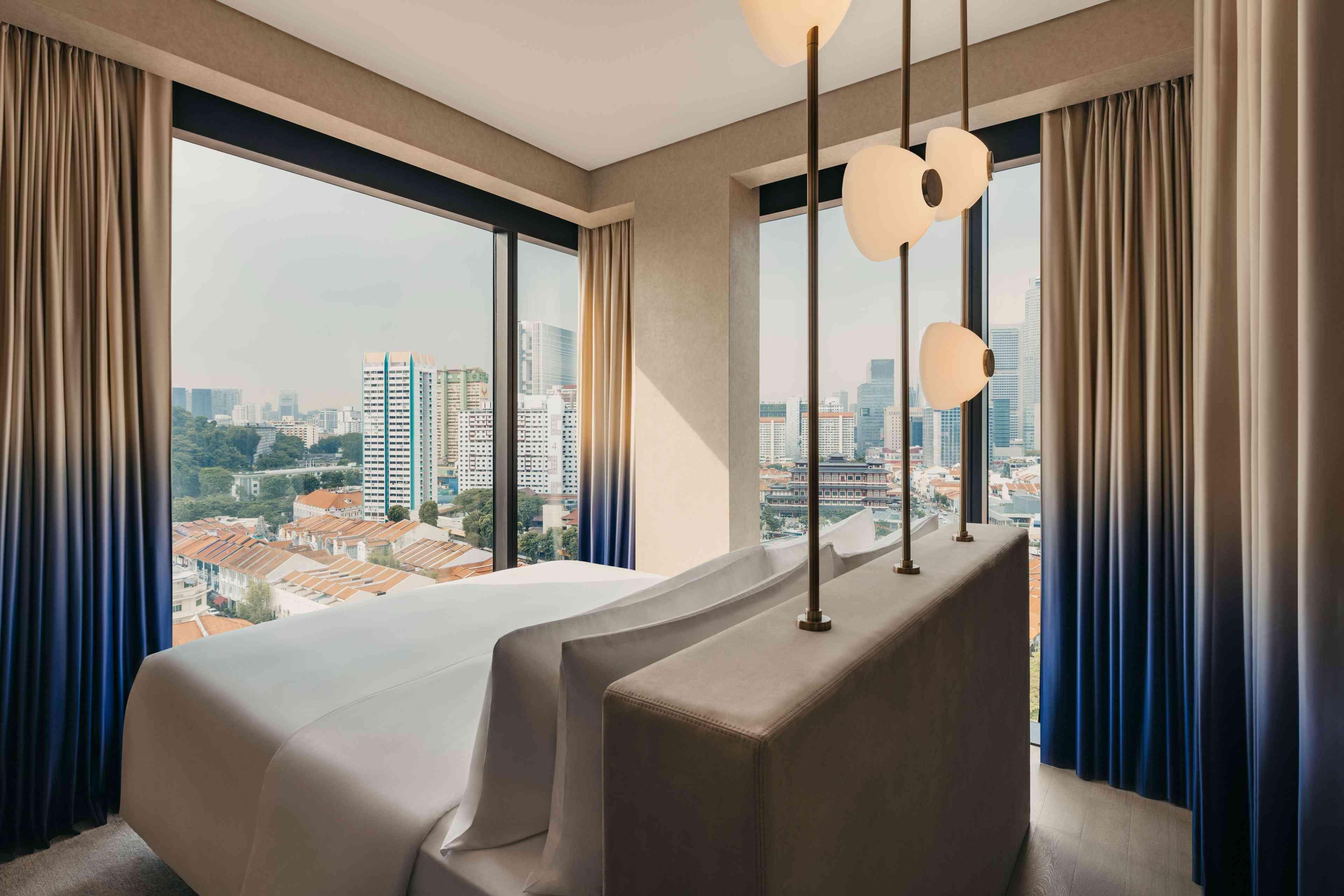 도시가 내려다보이는 천장부터 바닥까지 내려오는 대형 창문이 있는 Mondrian Singapore Duxton의 스위트룸입니다. 